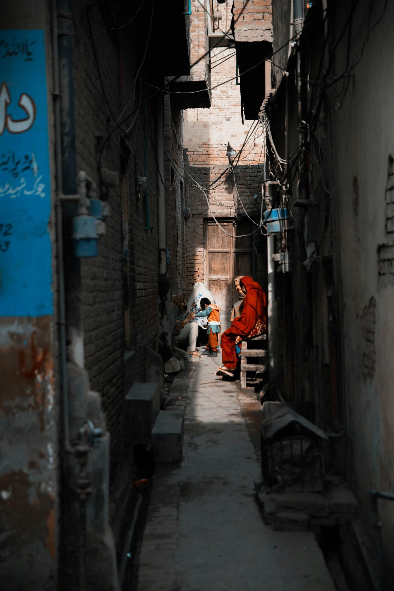 A vibrant scene in a narrow alleyway in Chiniot, captured in warm afternoon light.