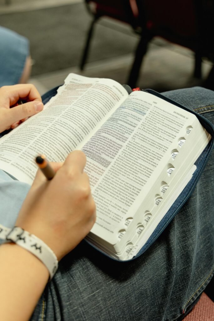 Close-up of a person taking notes in an open Bible, enhancing study focus.